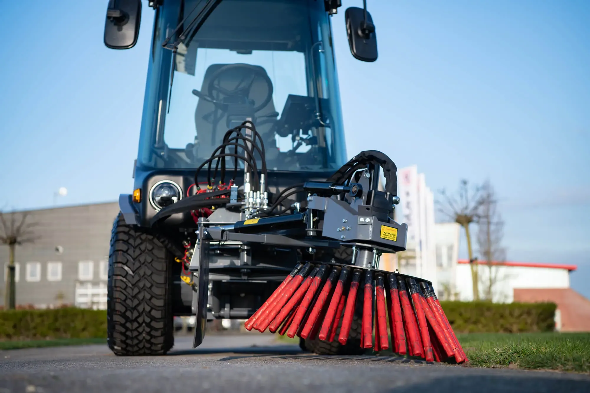 LM Trac machine removing weeds from a city pavement using a brush.